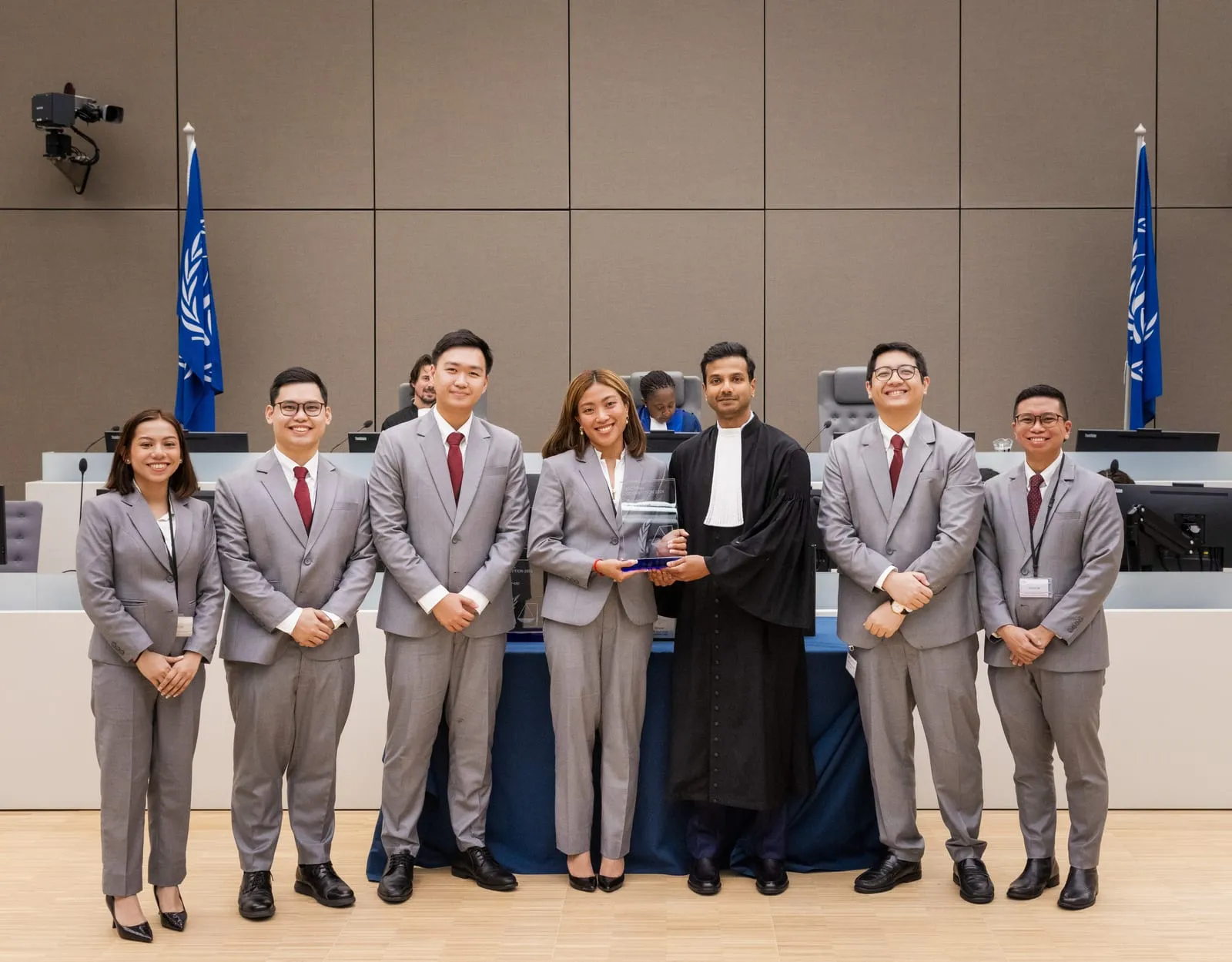 Farhaan Ahmed, in advocate's robes, presenting the winner's award to a team in the ICC courtroom at the Final of the 2024 English edition of the ICC Moot Court Competition