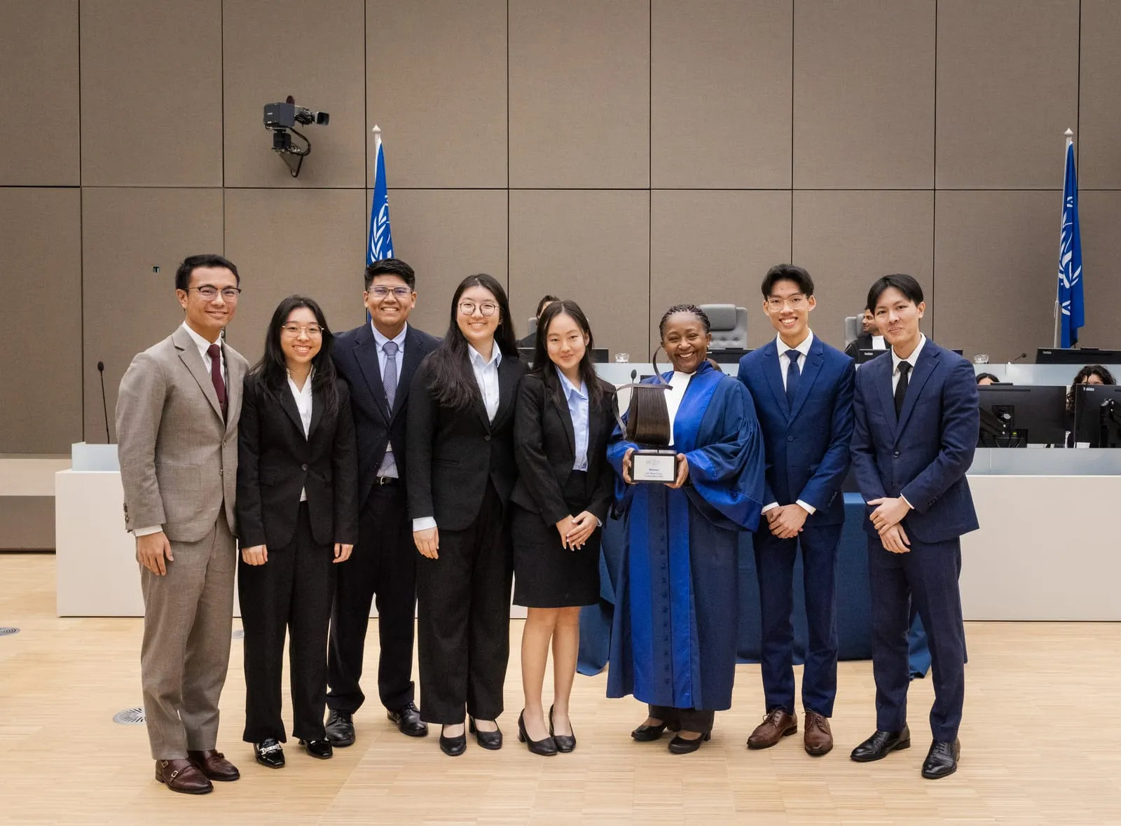 The winning team with a judge holding the winner's trophy at the Final of the 2024 English edition of the ICC Moot Court Competition
